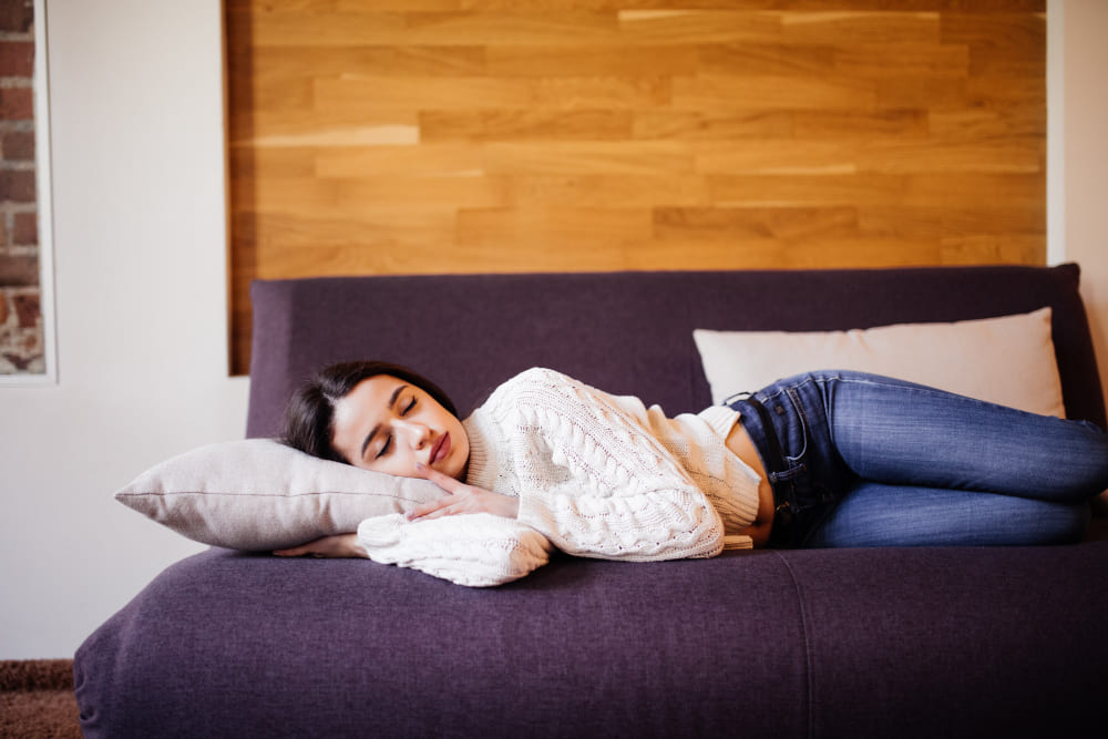 A-woman-lying-comfortably-on-a-couch-resting-her-head-on-a-pillow